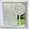 A window with a translucent film decorated with a repeating pattern of simple bird line drawings. One section is magnified to show the bird design clearly. The window looks out onto a green garden.