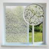 A window with a leafy-patterned frosted film partially open to reveal a garden outside. A magnifying glass highlights the green leaf pattern on the window film.